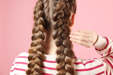 Woman with braided hair on pink background, back view