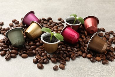 Photo of Coffee capsules with seedlings and beans on light grey table