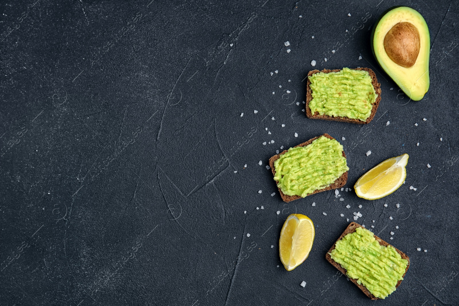 Photo of Flat lay composition with crisp rye toasts and avocado on dark table