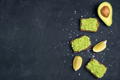 Photo of Flat lay composition with crisp rye toasts and avocado on dark table