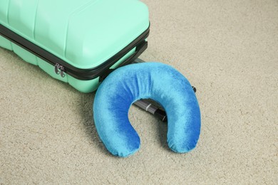 Photo of Light blue travel pillow and suitcase on beige rug