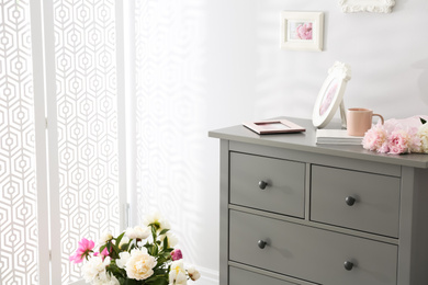 Grey chest of drawers in stylish room interior. Space for text
