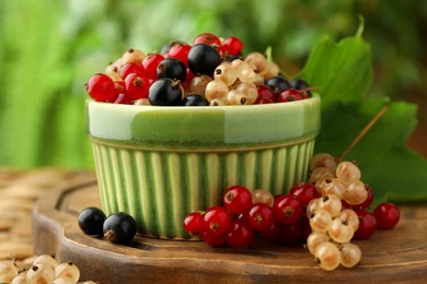 Different fresh ripe currants and green leaf on table, closeup