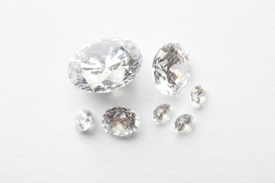 Photo of Many beautiful shiny diamonds on white background, flat lay