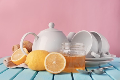 Lemons, jar with honey and crockery on table