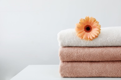 Photo of Stack of fresh towels with flower on table against white background. Space for text