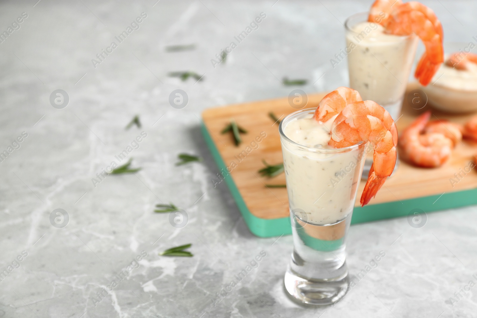 Photo of Glasses of shrimp cocktail and tartar sauce on marble table. Space for text