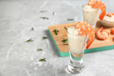 Photo of Glasses of shrimp cocktail and tartar sauce on marble table. Space for text