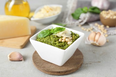 Photo of Bowl of delicious pesto sauce on light table, closeup