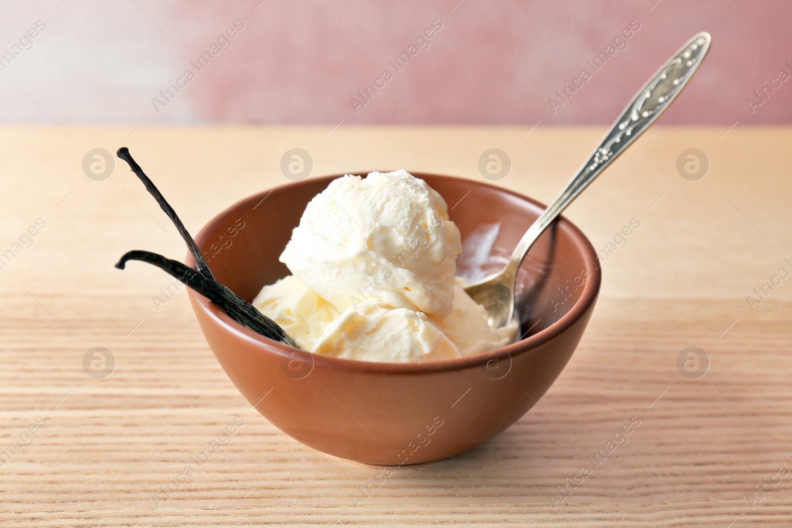 Photo of Bowl with tasty vanilla ice cream on wooden table