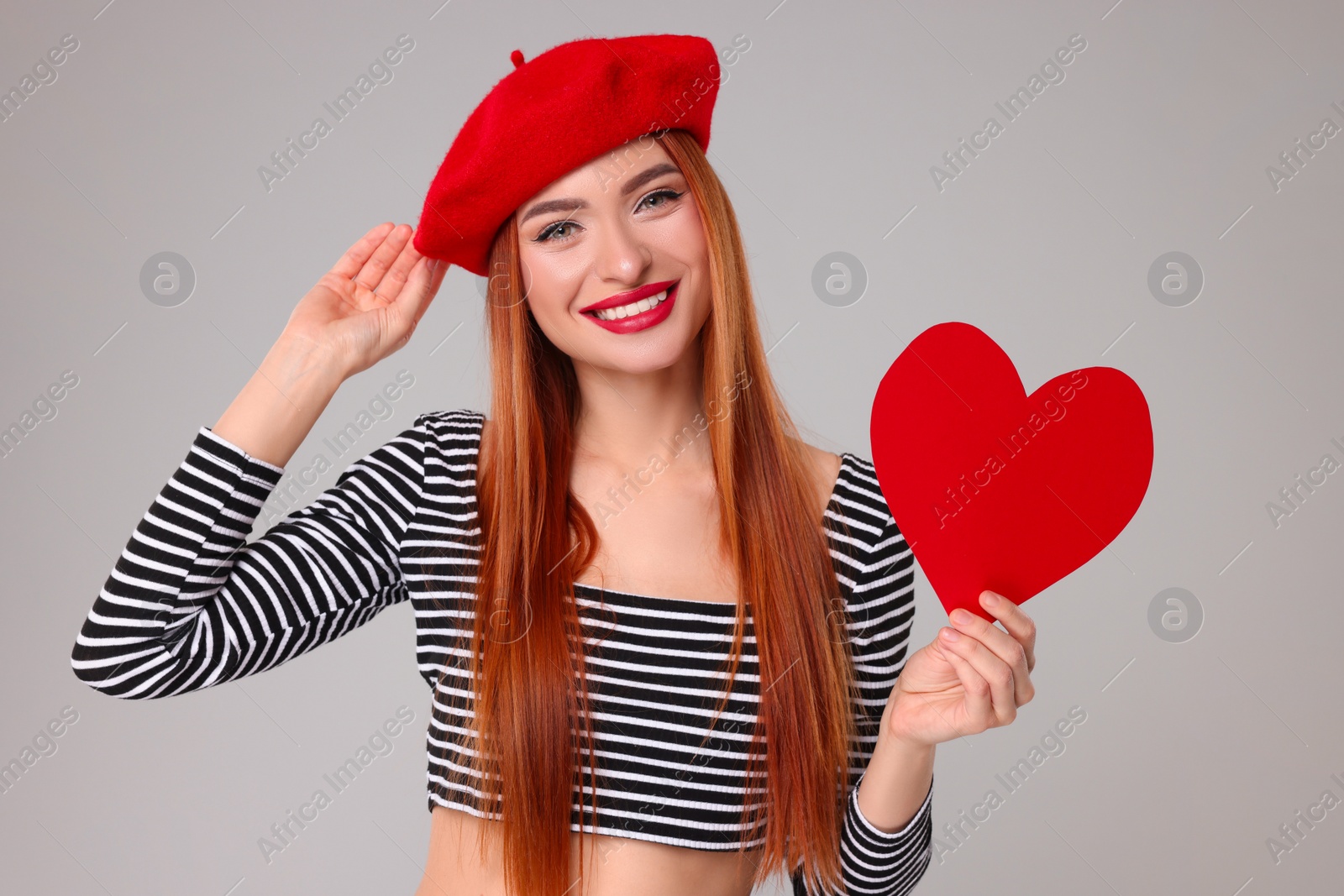 Photo of Young woman with paper heart on light grey background