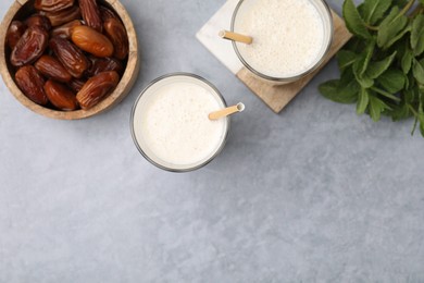 Photo of Glasses of delicious date smoothie, dried fruits and mint on light grey table, flat lay. Space for text