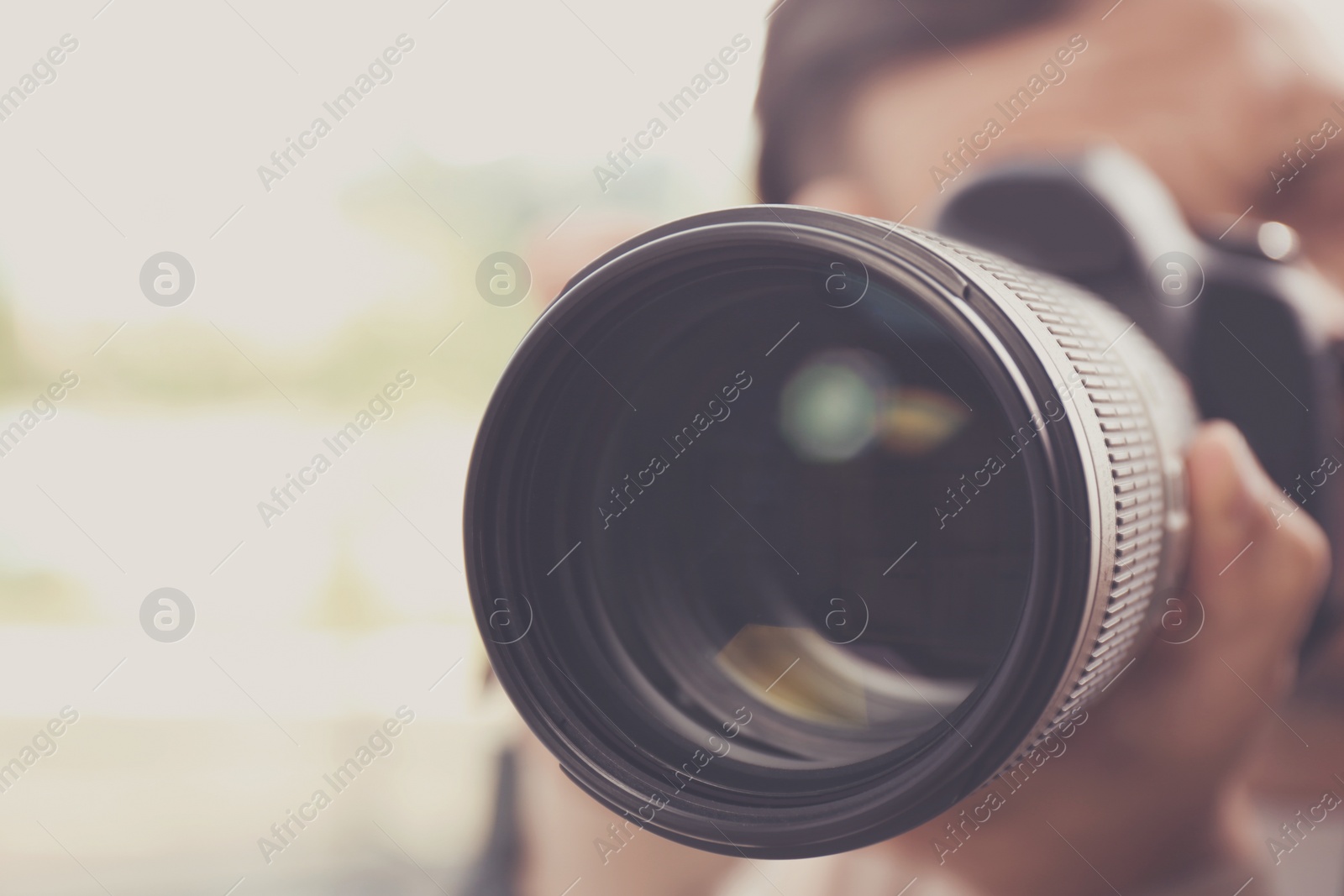 Image of Professional photographer with camera on blurred background, closeup