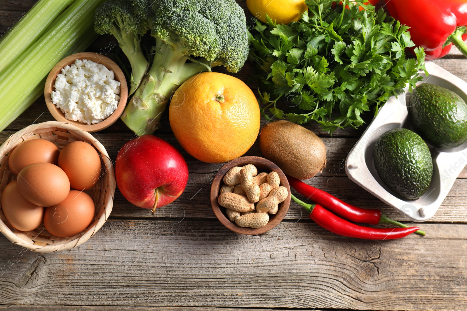 Photo of Healthy meal. Different vegetables and raw eggs on wooden table, flat lay