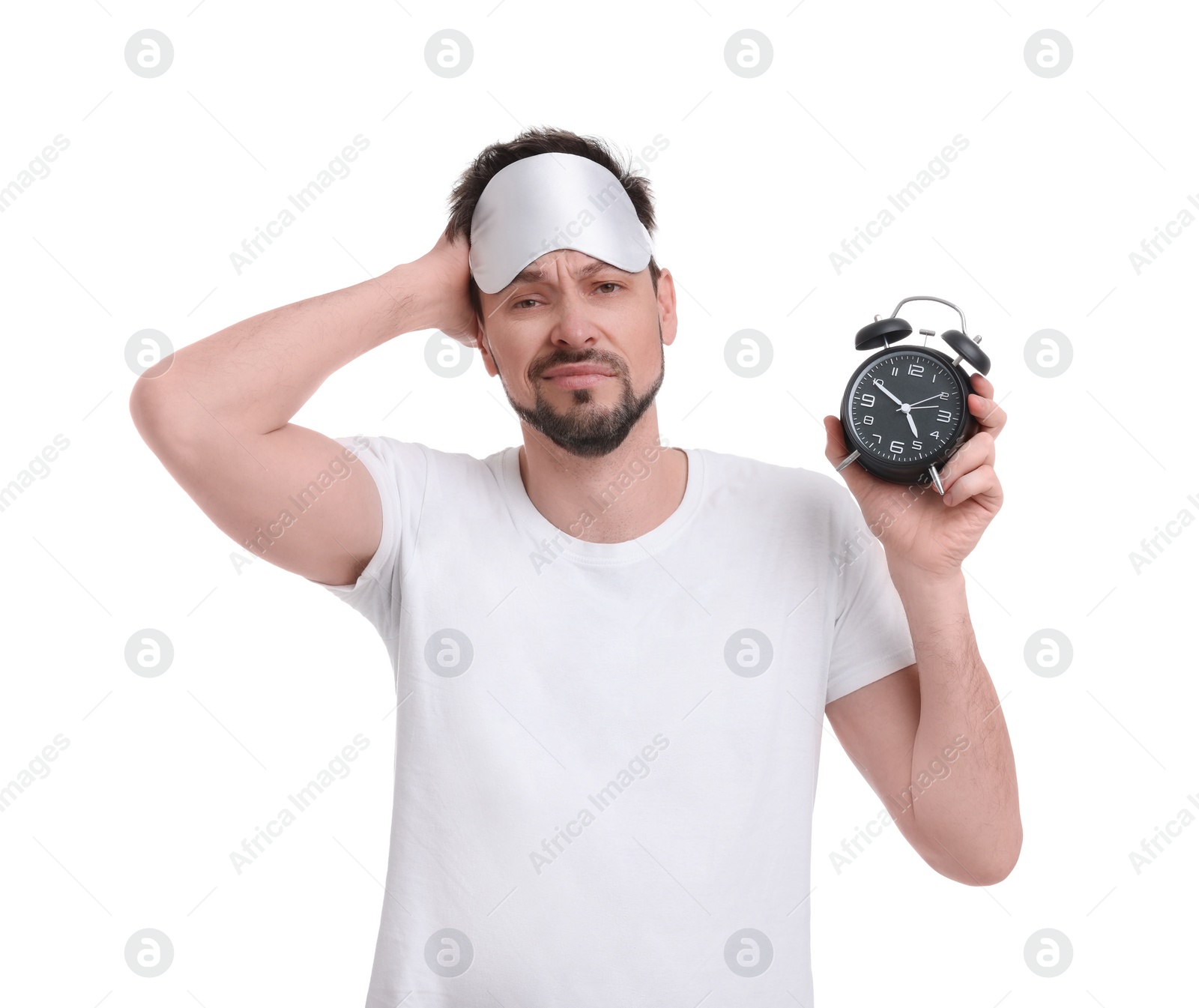 Photo of Tired man with sleep mask and alarm clock on white background. Insomnia problem