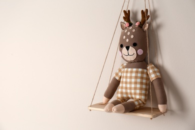 Photo of Shelf with cute toy deer on beige wall, space for text. Child's room interior element