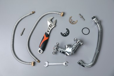 Photo of Parts of water tap and wrenches on grey background, flat lay