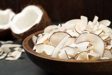 Photo of Tasty coconut chips on black table, closeup