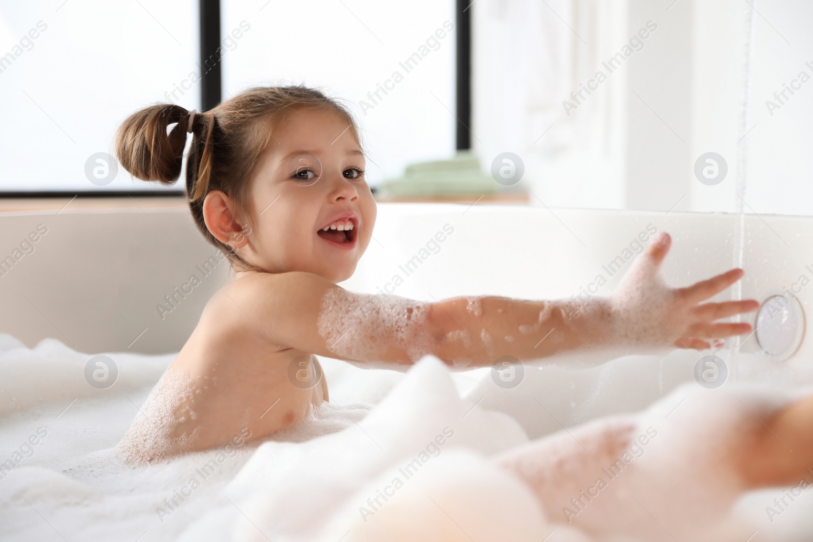 Photo of Cute little girl taking bubble bath at home