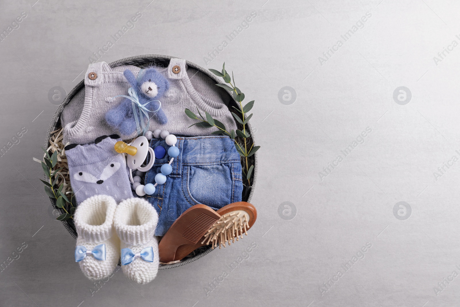 Photo of Box with baby clothes, booties and accessories on grey background, top view. Space for text