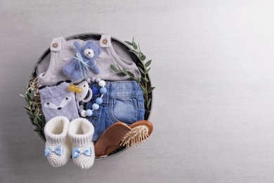 Box with baby clothes, booties and accessories on grey background, top view. Space for text