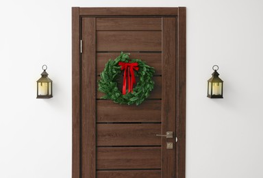 Photo of Beautiful Christmas wreath with red bow hanging on door