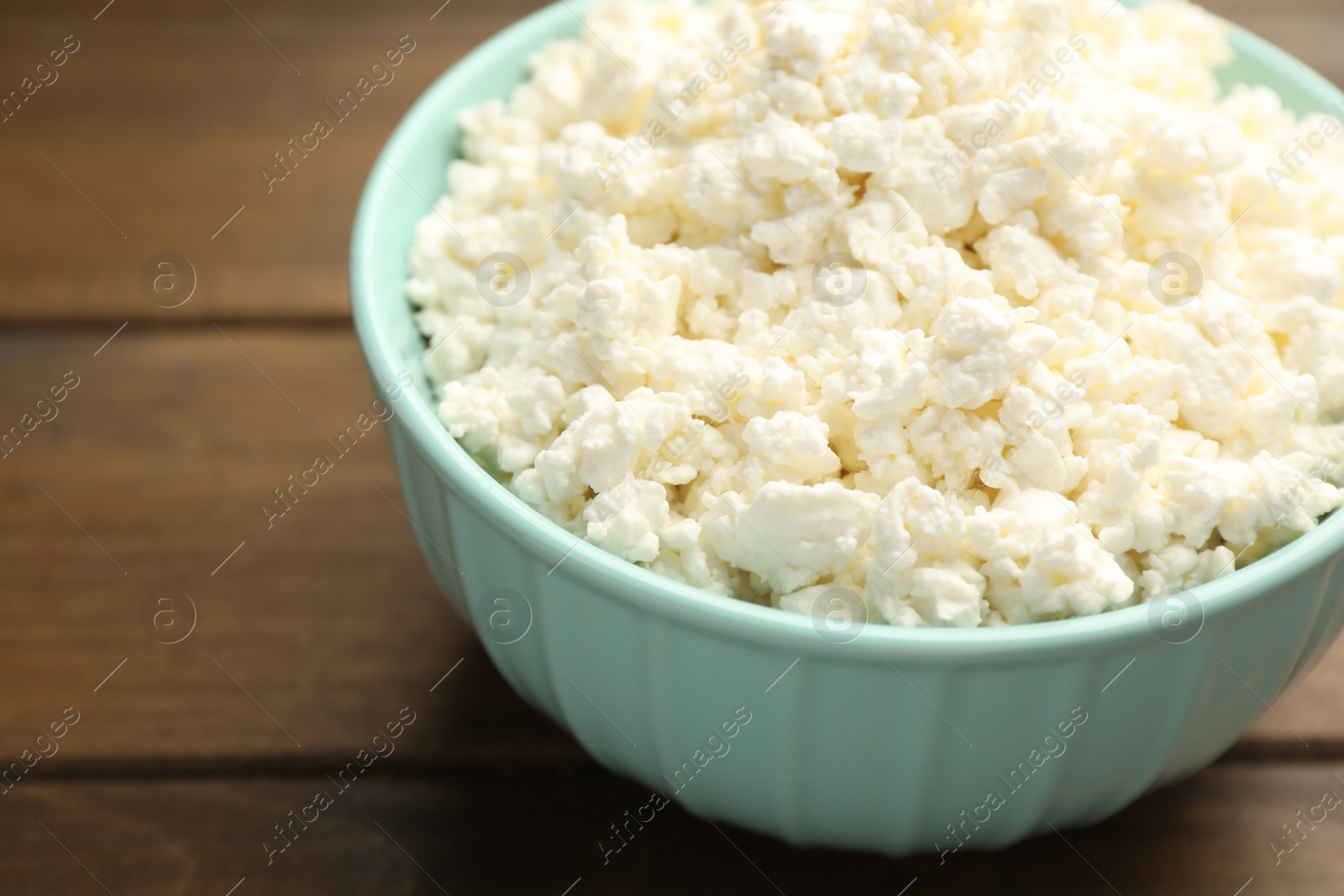 Photo of Delicious fresh cottage cheese on wooden table, closeup