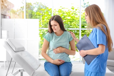 Young pregnant woman with depression and her doctor in clinic