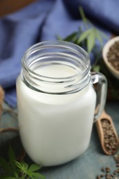 Photo of Mason jar of fresh hemp milk on light blue wooden table