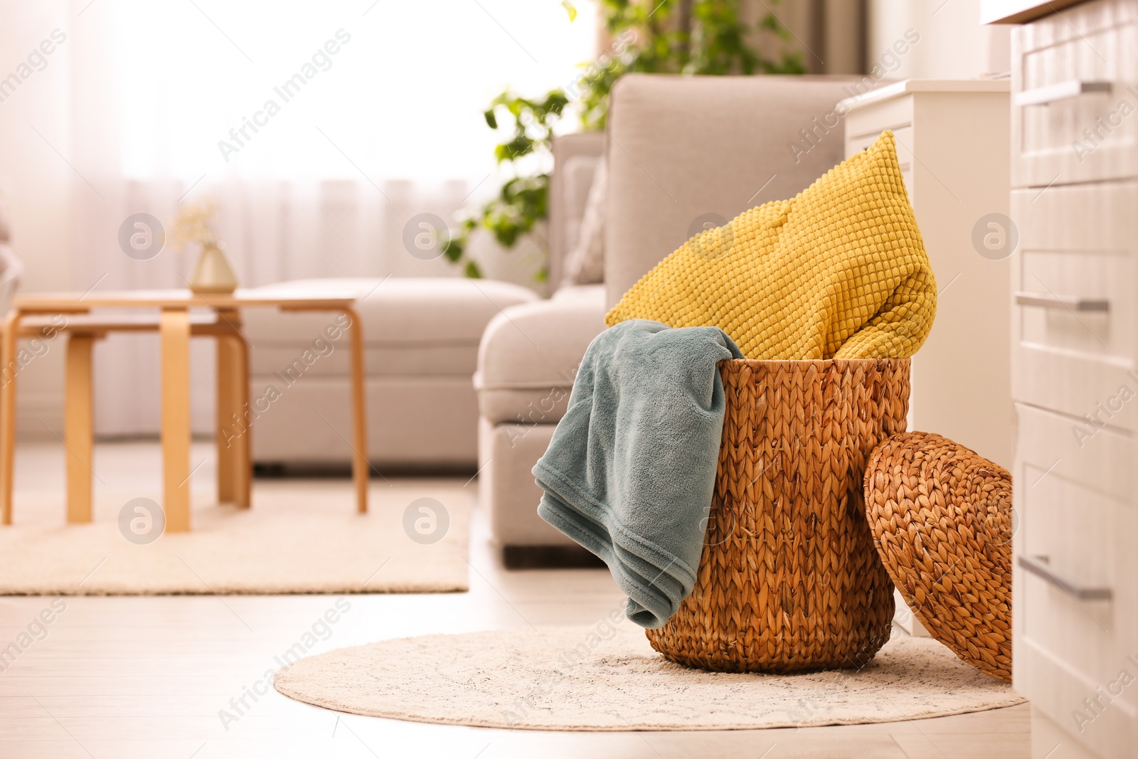 Photo of Basket with blanket and pillow in light room