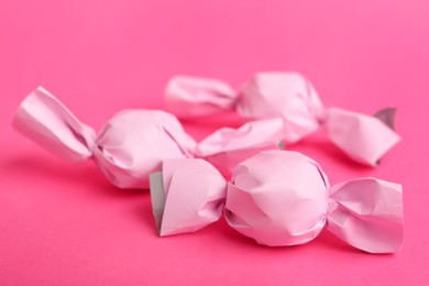 Photo of Candies in pink wrappers on bright background