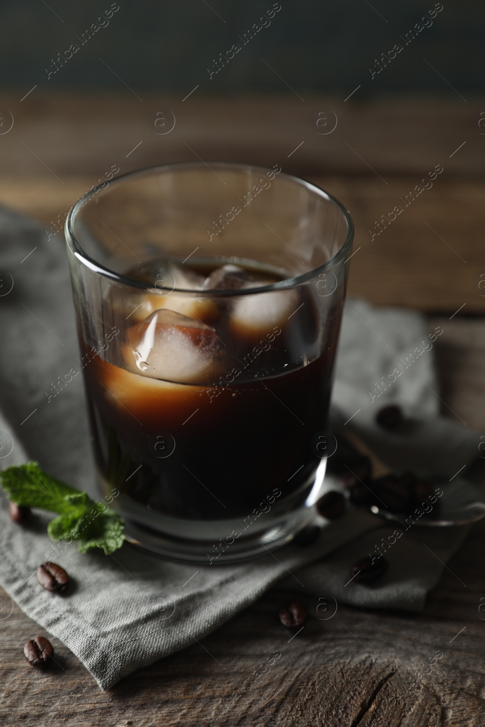 Photo of Glass of delicious iced coffee, mint and beans on wooden table