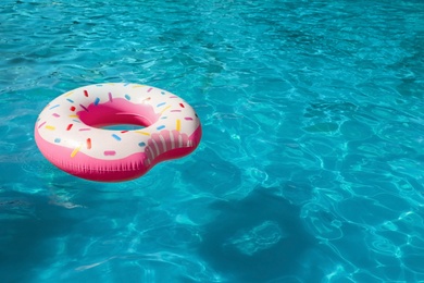 Inflatable ring floating in swimming pool on sunny day. Space for text