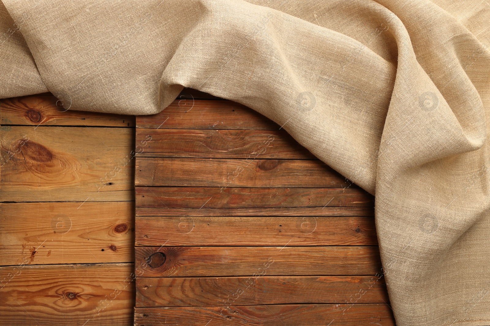 Photo of Burlap fabric on wooden table, top view. Space for text