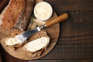 Tasty bread with butter and knife on wooden table, top view. Space for text