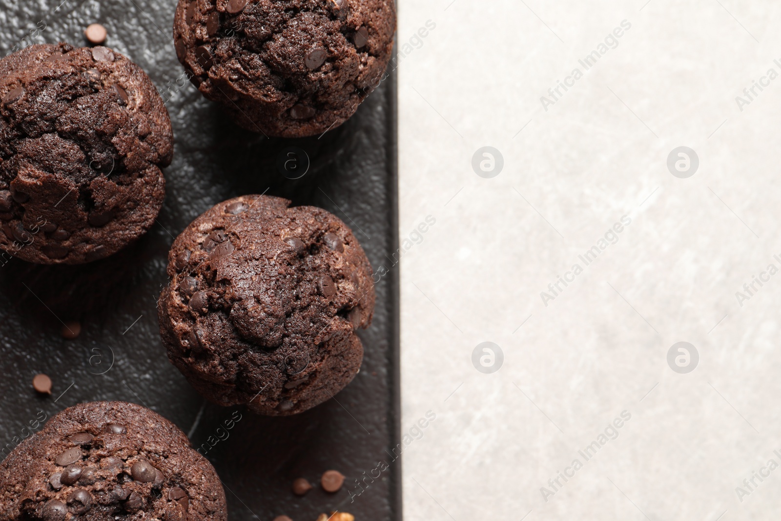 Photo of Delicious chocolate muffins on light table, top view. Space for text