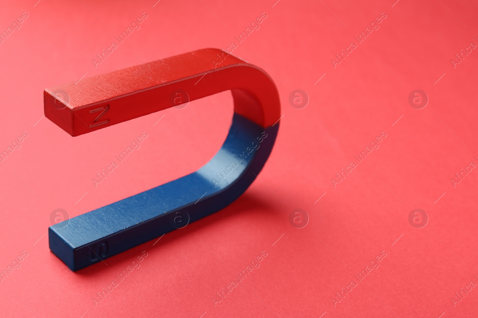 Photo of Red and blue horseshoe magnet on color background. Space for text