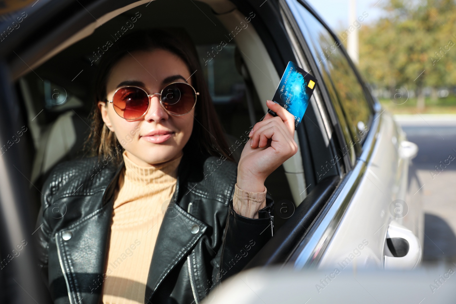 Photo of Woman sitting in car and giving credit card at gas station