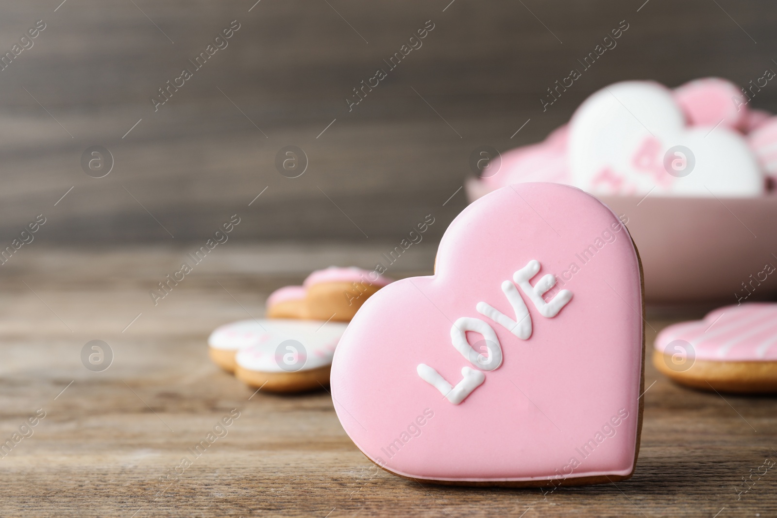 Photo of Heart shaped cookie with word Love on wooden table, closeup and space for text. Valentine's day treat