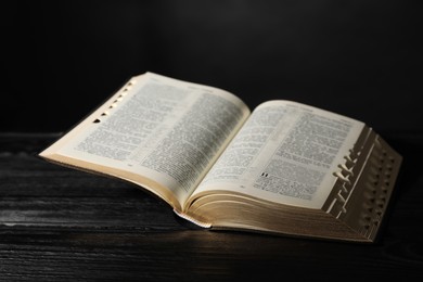 Photo of Open Bible on black wooden table. Christian religious book