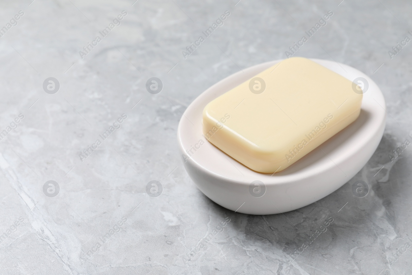 Photo of Dish with soap bar on light grey table, space for text
