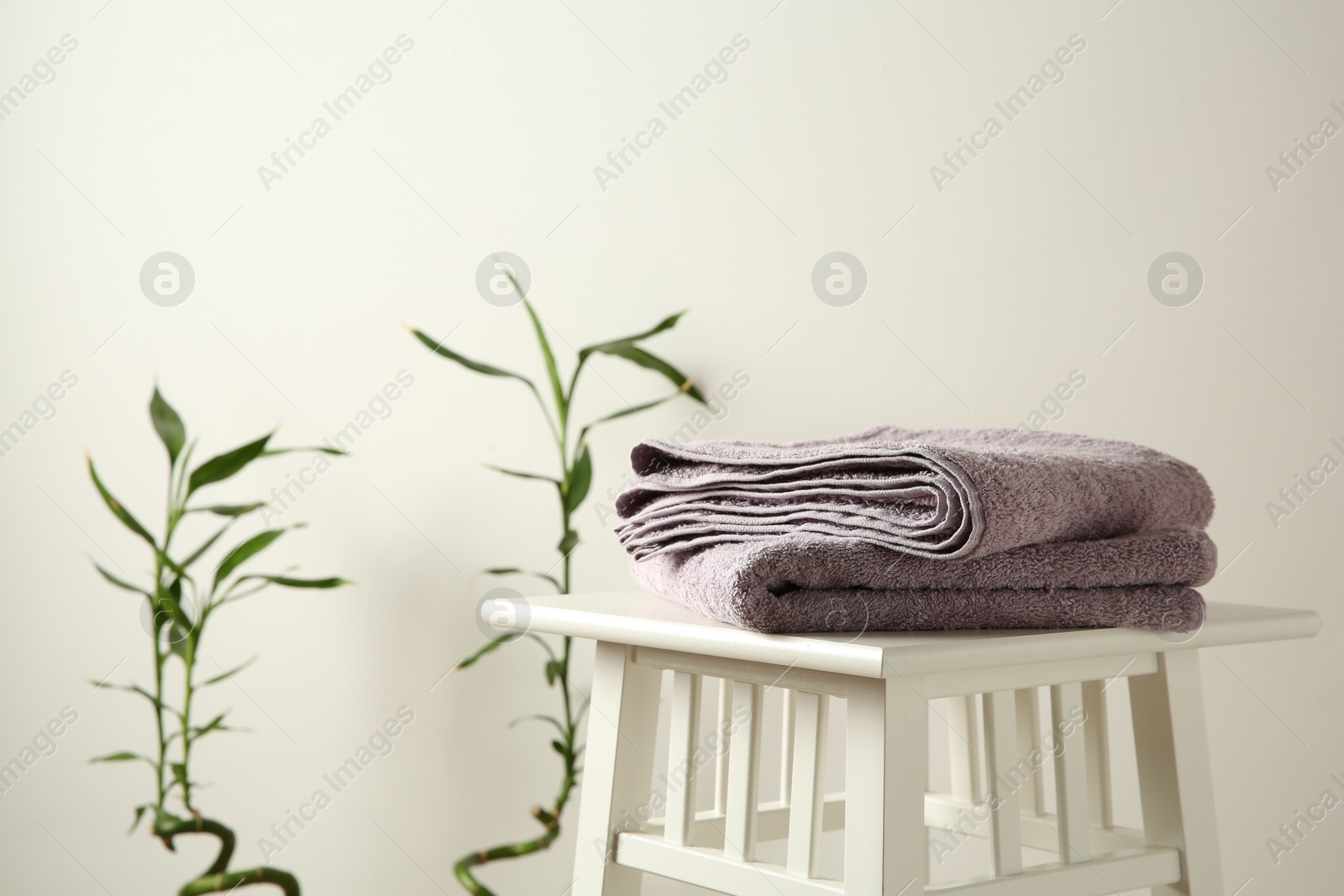 Photo of Violet towels on stool against white wall. Space for text