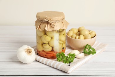 Tasty pickled mushrooms and spices on white wooden table