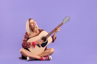 Photo of Happy hippie woman playing guitar on purple background. Space for text
