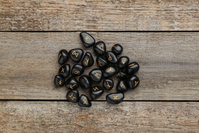 Pile of black rune stones on wooden table, flat lay