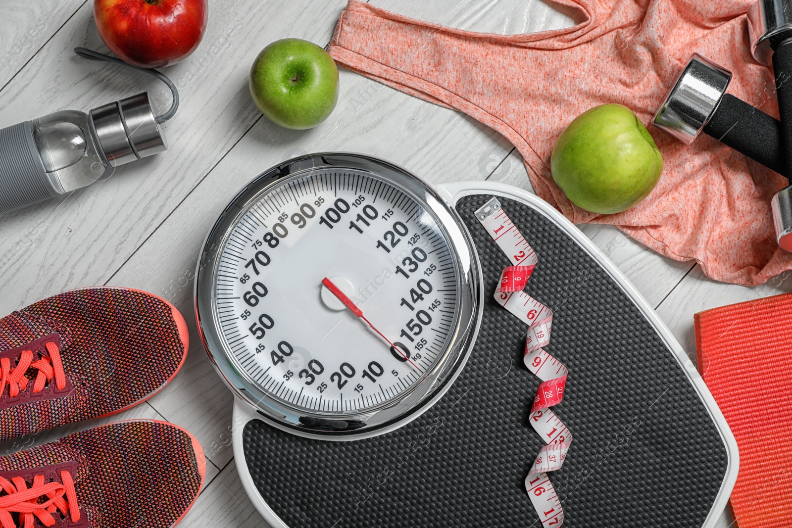 Photo of Flat lay composition with scales, apples and sport equipment on wooden background. Weight loss