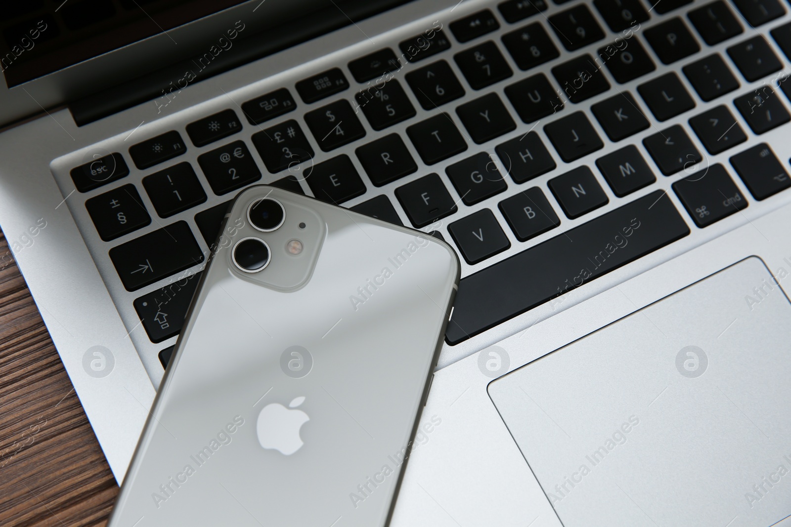 Photo of MYKOLAIV, UKRAINE - JULY 20, 2020: iPhone 11 and MacBook on wooden table, closeup