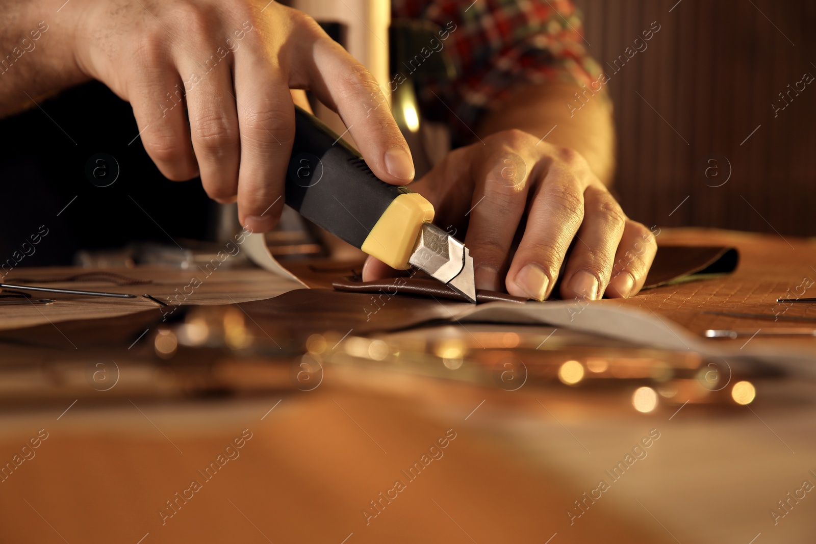 Photo of Man cutting leather with knife at table, closeup