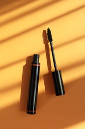 Photo of Mascara for eyelashes on orange background, flat lay. Makeup product