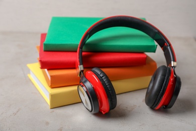 Photo of Modern headphones with hardcover books on grey table